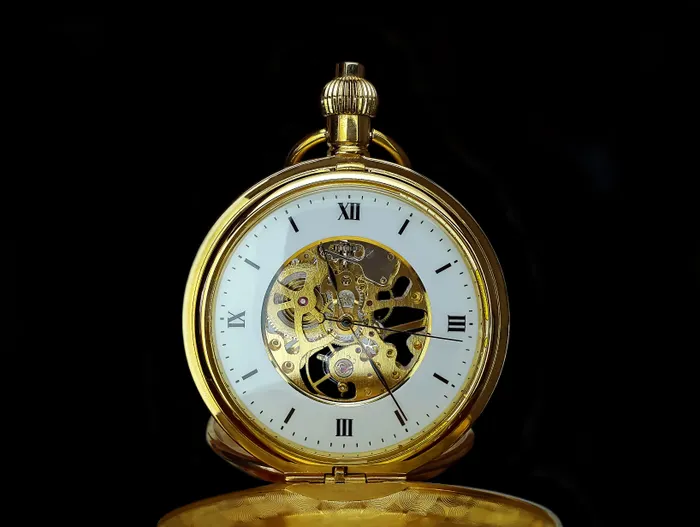 Gold skeleton mechanical pocket watch on a black background